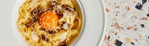 Vue du dessus de délicieuses pâtes carbonara servies en assiette ronde sur table en pierre, vue panoramique — Photo de stock