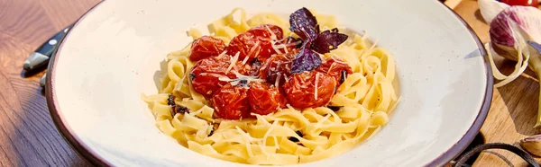 Deliziosa pasta con pomodori, parmigiano e basilico rosso servita sul tavolo in legno alla luce del sole, colpo panoramico — Foto stock