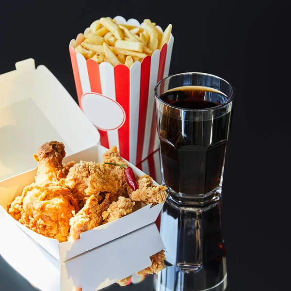 Pollo frito, papas fritas y refrescos en vidrio sobre mesa de vidrio - foto de stock