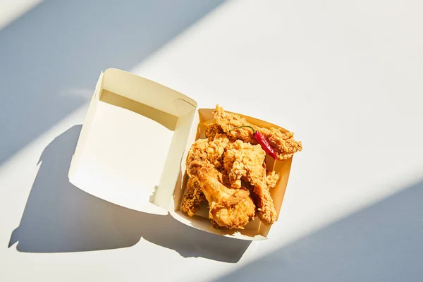 Vista superior de frango frito picante e saboroso com pimenta na mesa branca à luz do sol — Fotografia de Stock