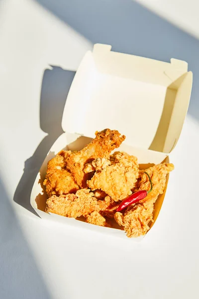 Leckeres und würziges frittiertes Huhn mit Chilipfeffer auf weißem Tisch im Sonnenlicht — Stockfoto