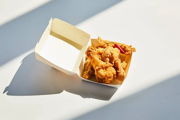 Tasty and spicy deep fried chicken with chili pepper on white table in sunlight — Stock Photo