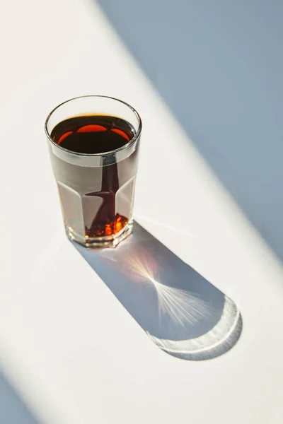 Savoureux soda en verre sur table blanche à la lumière du soleil avec ombre — Photo de stock