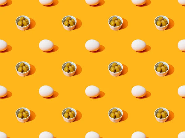 Huevos de pollo blanco fresco y aceitunas sobre fondo de color naranja, patrón sin costuras - foto de stock