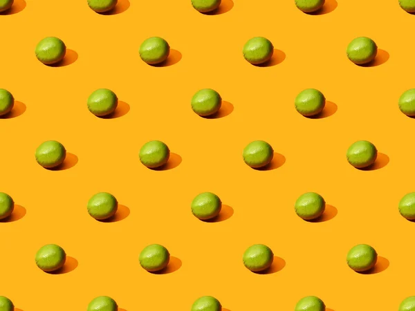 Limes entières fraîches sur fond orange coloré, motif sans couture — Photo de stock