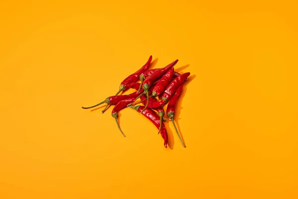 Vista superior de los chiles picantes rojos sobre fondo de color naranja - foto de stock