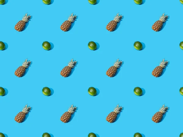 Top view of whole ripe pineapples and limes on blue colorful background, seamless pattern — Stock Photo