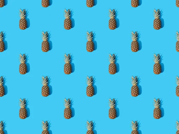 Vue de dessus d'ananas mûrs entiers sur fond bleu coloré, motif sans couture — Photo de stock