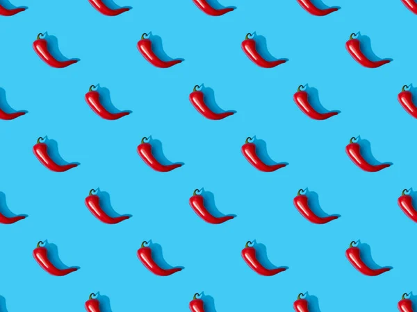Vista superior de los chiles picantes rojos sobre fondo colorido azul, patrón sin costuras - foto de stock