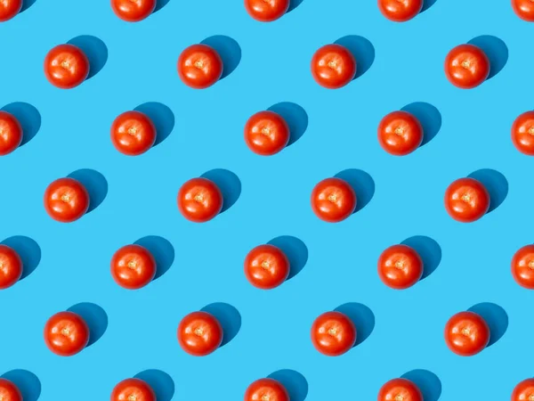 Vue de dessus des tomates fraîches sur fond bleu coloré, motif sans couture — Photo de stock