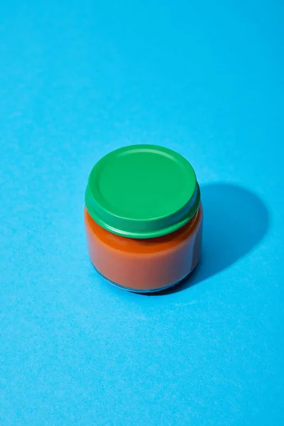 Fresh tomato puree in glass jar on blue colorful background — Stock Photo