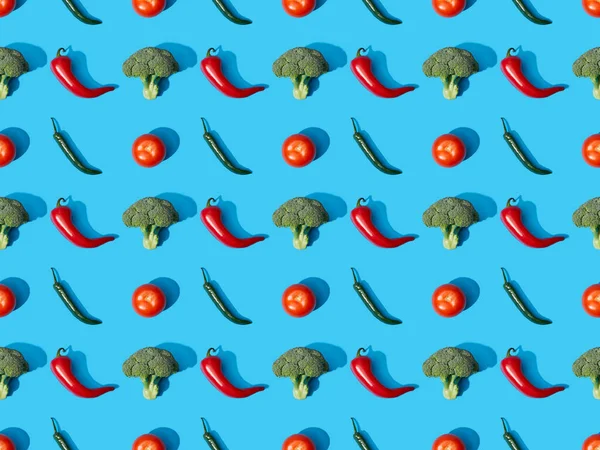 Top view of fresh green broccoli, chili peppers and tomatoes on blue background, seamless pattern — Stock Photo