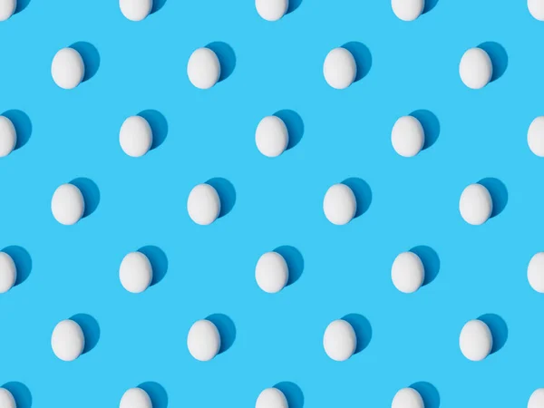 Вид зверху на свіжі курячі яйця на синьому фоні, безшовний візерунок — стокове фото