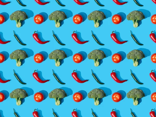 Vista dall'alto di broccoli verdi freschi, peperoncini e pomodori su sfondo blu, modello senza cuciture — Foto stock