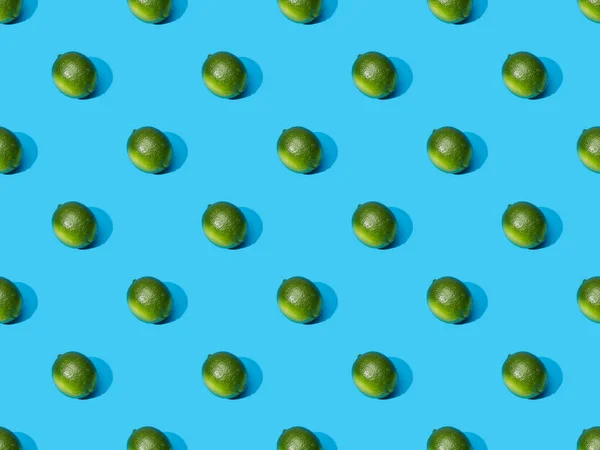 Limes entières fraîches sur fond bleu coloré, motif sans couture — Photo de stock