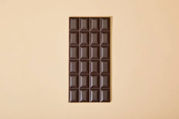Vista superior de la barra de chocolate negro dulce sobre fondo beige - foto de stock