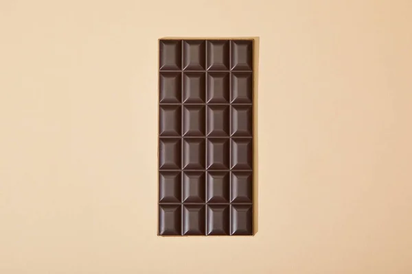 Vue du dessus de la barre de chocolat noir sucré sur fond beige — Photo de stock