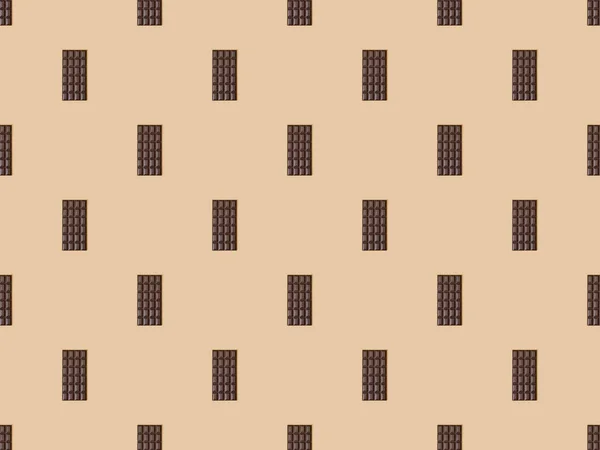 Vista superior de barras de chocolate escuro doce no fundo bege, padrão sem costura — Fotografia de Stock