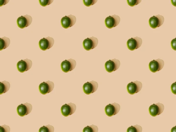 Top view of fresh whole limes on beige background, seamless pattern — Stock Photo