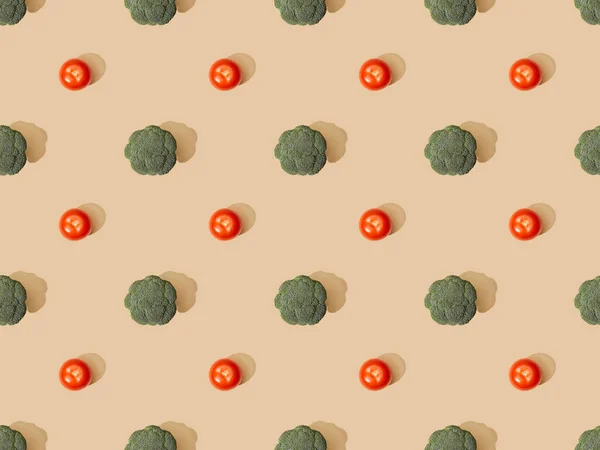 Top view of fresh green broccoli and tomatoes on beige background, seamless pattern — Stock Photo