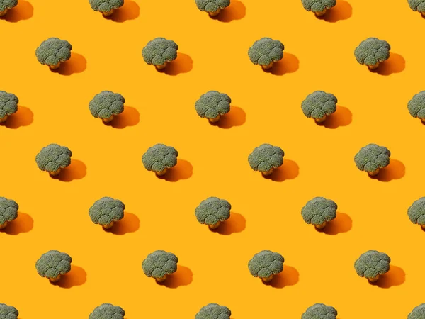 Frischer grüner Brokkoli auf orangefarbenem Hintergrund, nahtloses Muster — Stockfoto