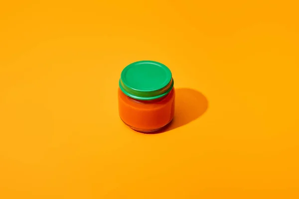 Fresh tomato puree in glass jar on orange colorful background — Stock Photo