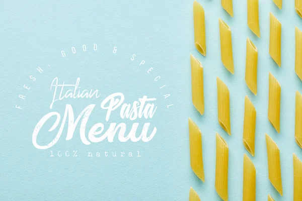 Flat lay with raw penne on blue background with Italian pasta menu illustration — Stock Photo