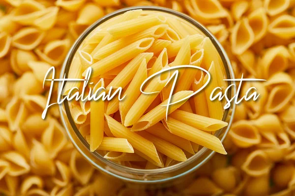 Top view of raw penne in jar and around with Italian pasta illustration — Stock Photo