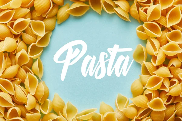 Cornice rotonda di Conchiglie crude su sfondo blu con illustrazione pasta — Foto stock