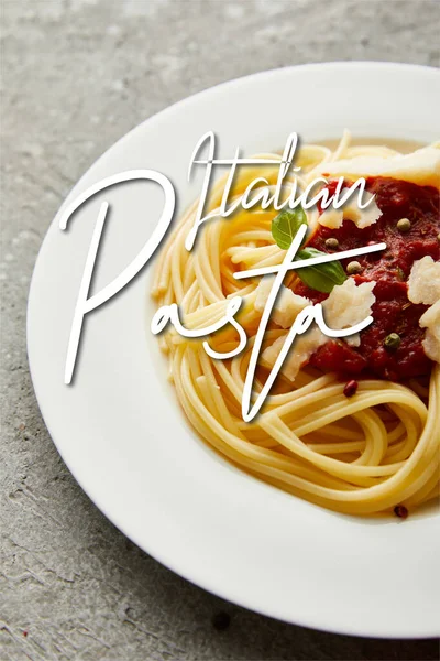 Deliciosos espaguetis con salsa de tomate en plato sobre superficie texturizada gris con ilustración de pasta italiana - foto de stock