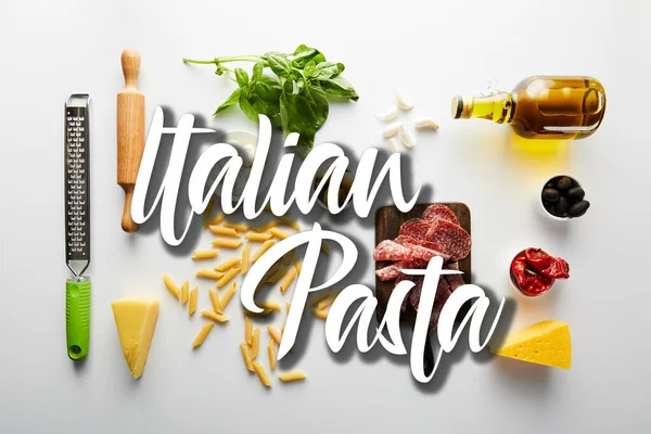 Acostado plano con plato de carne, botella de aceite de oliva, rodillo, rallador e ingredientes sobre fondo blanco, ilustración de pasta italiana - foto de stock