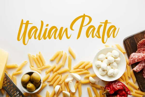 Vista superior de penne, bandeja de carne, rallador e ingredientes sobre fondo blanco, ilustración de pasta italiana - foto de stock