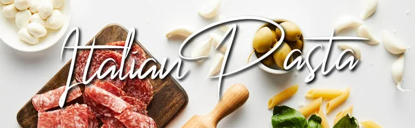 Panoramic orientation of meat platter, rolling pin, pasta, garlic and bowls with olives and mozzarella on white background, italian pasta illustration — Stock Photo