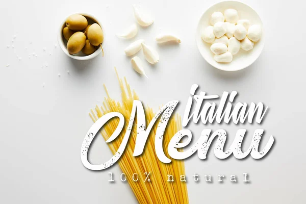 Draufsicht auf Spaghetti, Knoblauch, Meersalz und Schalen mit Oliven und Mozzarella auf weißem Hintergrund, italienische Menüillustration — Stockfoto