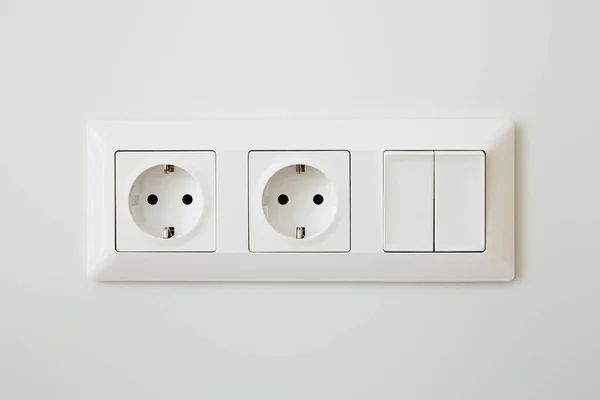 Power sockets near switch on white wall — Stock Photo