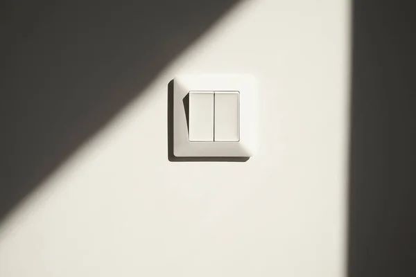 Sunshine on white switch on wall in apartment — Stock Photo