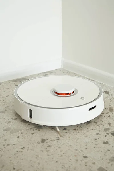 Modern robotic vacuum cleaner washing floor tiles near white walls — Stock Photo