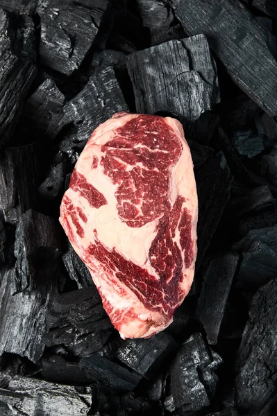 Vue de dessus du steak cru frais sur les charbons noirs — Photo de stock