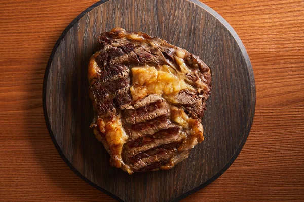 Vue de dessus de steak grillé savoureux servi sur une planche en bois — Photo de stock