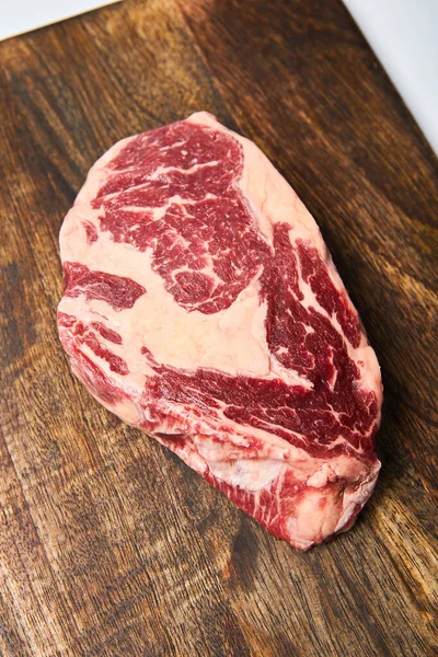 Draufsicht auf frisches rohes Steak auf Holzschneidebrett — Stockfoto