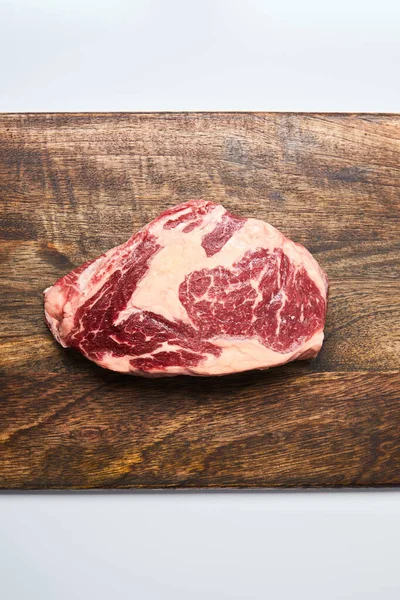 Vue du dessus du steak cru frais sur planche à découper en bois sur fond blanc — Photo de stock