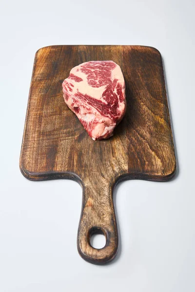 Fresh raw steak on wooden cutting board on white background — Stock Photo