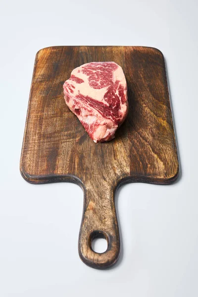 Bistecca fresca cruda su tagliere di legno su sfondo bianco — Foto stock