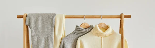 Beige gestrickte weiche Pullover und Hosen hängen auf Holzbügel auf weißem Hintergrund — Stockfoto