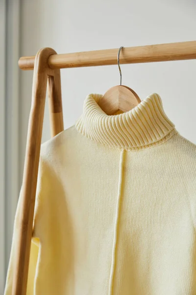 Vista da vicino di maglione morbido in maglia beige appeso su appendino in legno isolato su bianco — Foto stock