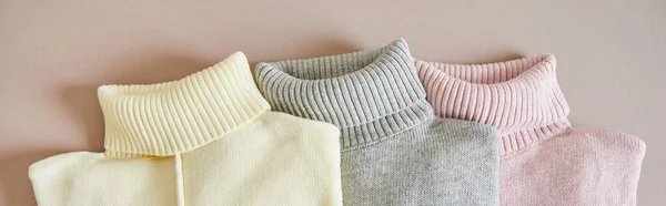 Top view of pink, beige and grey knitted soft sweaters, panoramic shot — Stock Photo