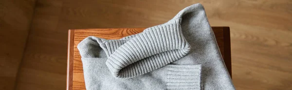 Vue du dessus du pull doux tricoté gris sur table en bois dans la chambre, vue panoramique — Photo de stock