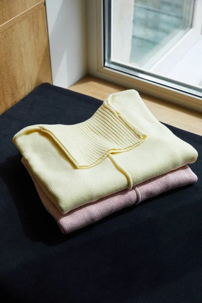 Suéteres suaves de punto rosa, beige en la superficie negra en la ventana - foto de stock