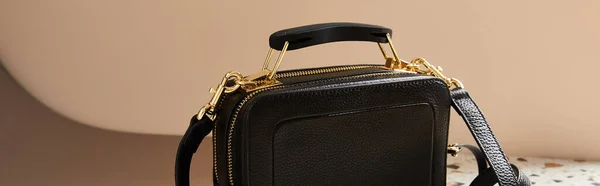 Borsa in pelle nera con cerniere dorate su sfondo beige, scatto panoramico — Foto stock