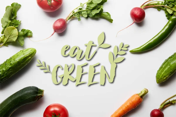 Vue du haut des légumes crus savoureux avec des feuilles vertes sur fond blanc avec manger illustration verte — Photo de stock